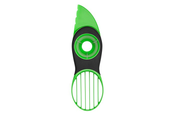 Green and black avocado slicer; splits, pits, and slices avocados with three-section design in a white background.