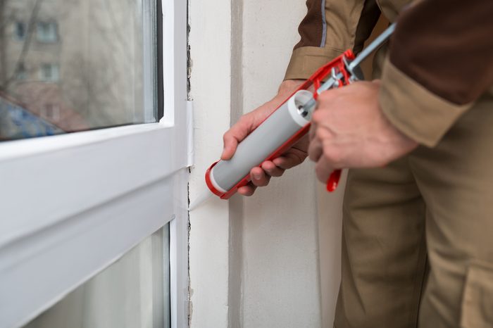 Close-up Of Person Hands Applying Silicone Sealant With Caulking Gun