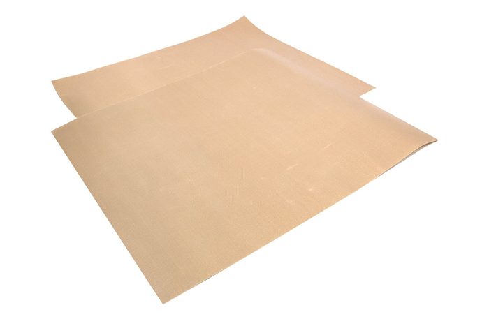 Two beige silicone baking mats lay flat, slightly overlapping, on a white background.