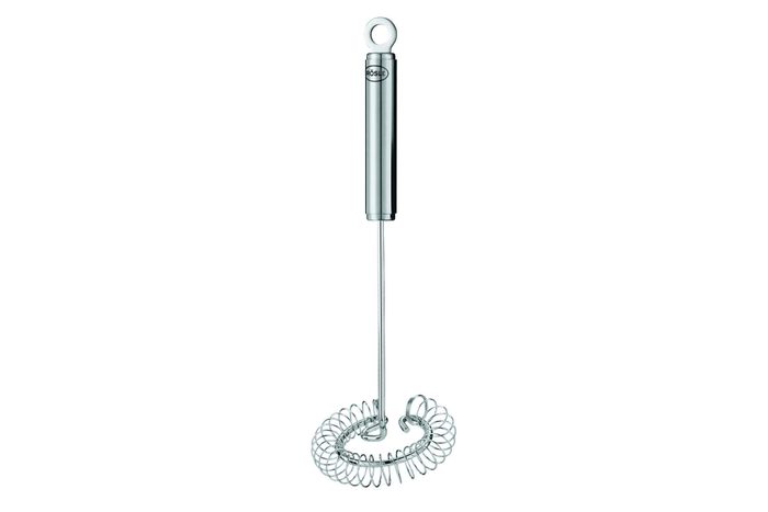 Metal whisk standing upright, featuring a circular handle and coiled stirring section; set against a plain white background.