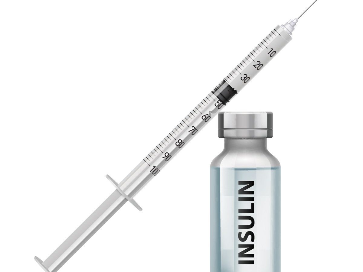 Syringe rests diagonally beside an insulin vial, filled with transparent liquid, against a plain white background. Text on the vial reads "INSULIN".