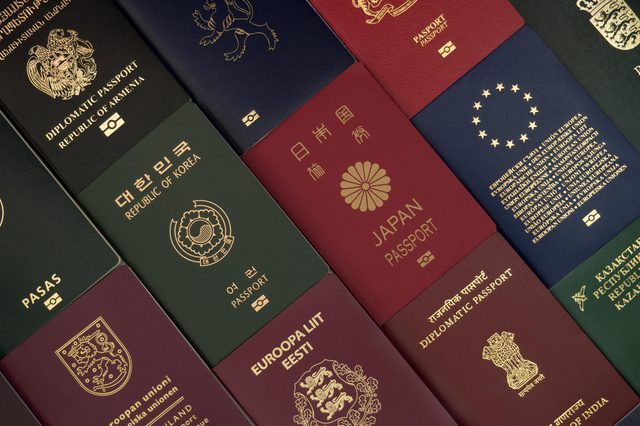 Passports lie on a surface, showcasing various countries' designs and languages, emphasizing international diversity and travel.