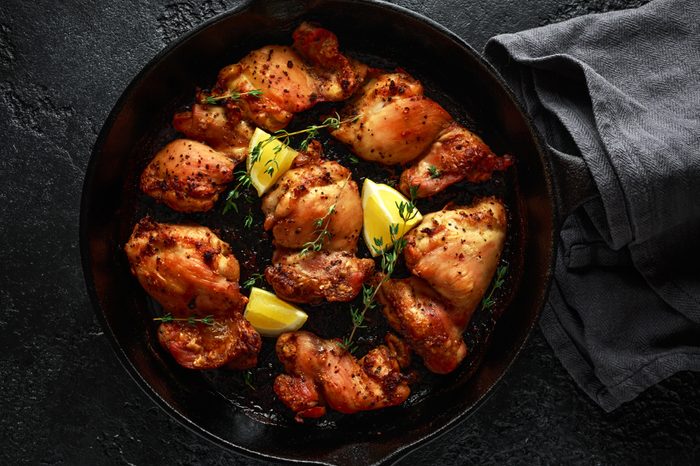 Roasted boneless skinless chicken thighs in lemon and thyme dressing served in vintage cast iron skillet, frying pan