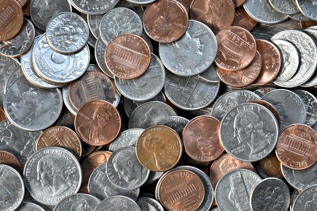 Coins lying scattered, include pennies, nickels, and quarters; mixed silver and copper colors, with US symbols and inscriptions visible.