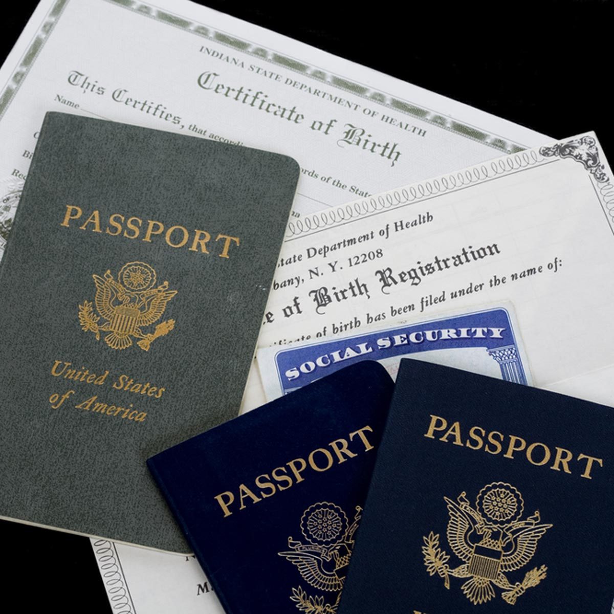 Passports lie on top of a birth certificate and a social security card, suggesting identity and citizenship documentation.