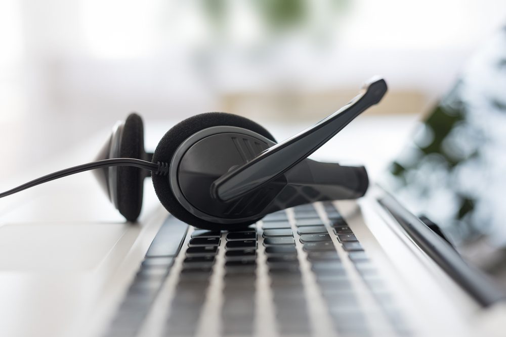 Communication support, call center and customer service help desk. VOIP headset on laptop computer keyboard.