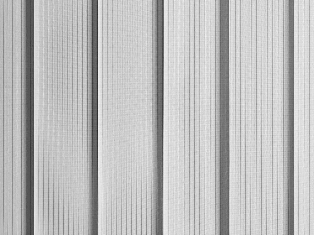 Vertical blinds create alternating light and dark stripes in a monochrome setting.