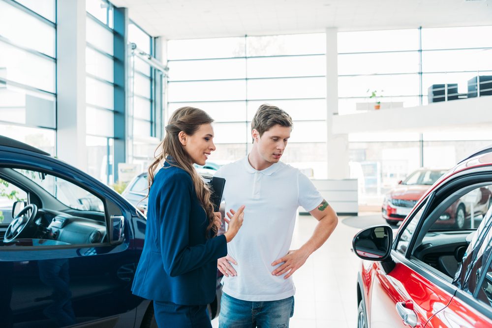 Sales manager describing car to customer in showroom