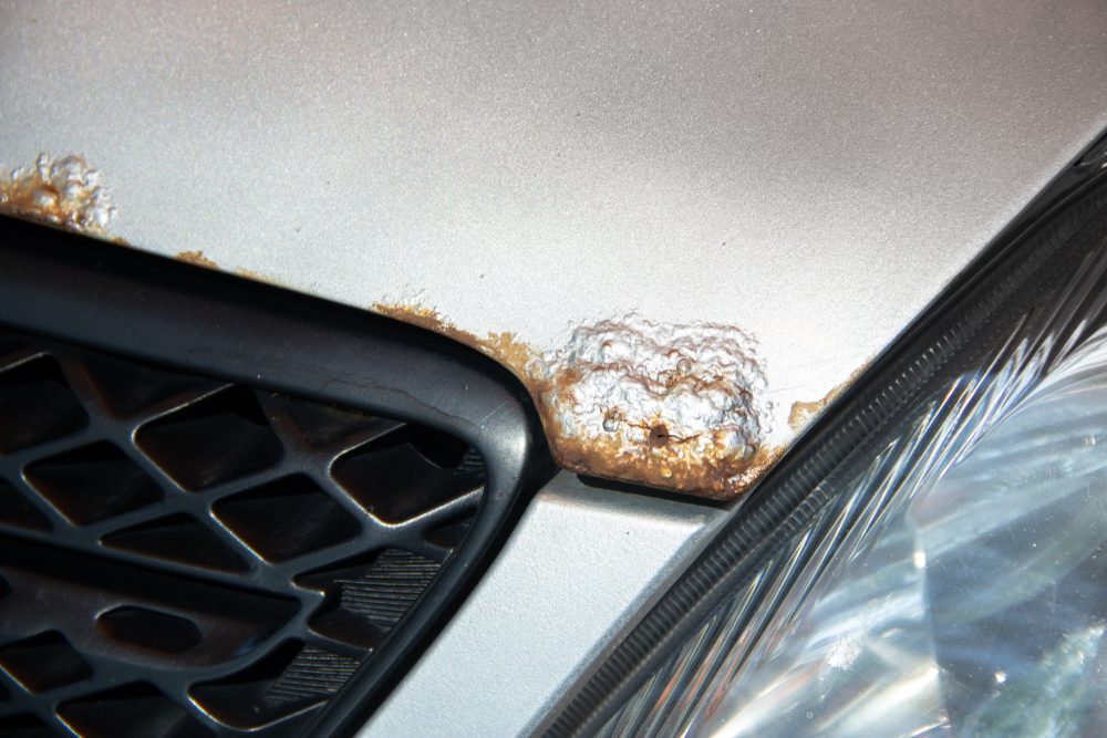 Rust on the bonnet of a silver car with black radiator grille