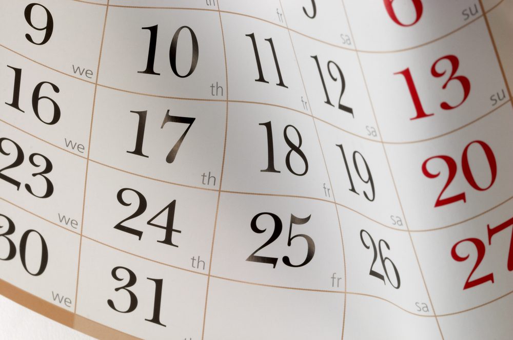 Calendar displays numbered days, some in black and others in red, representing dates. Days of the week are abbreviated below the numbers.