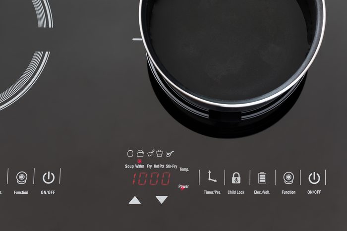 Boiling water at pan on Induction stove top panel, closeup