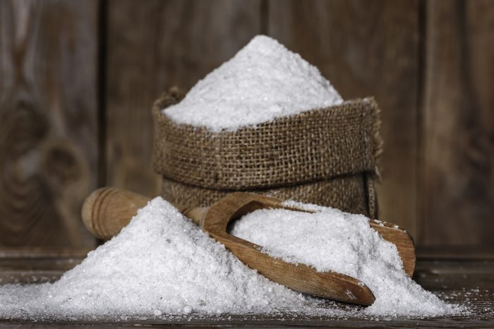 salt in bag and scoop closeup on the old wooden background