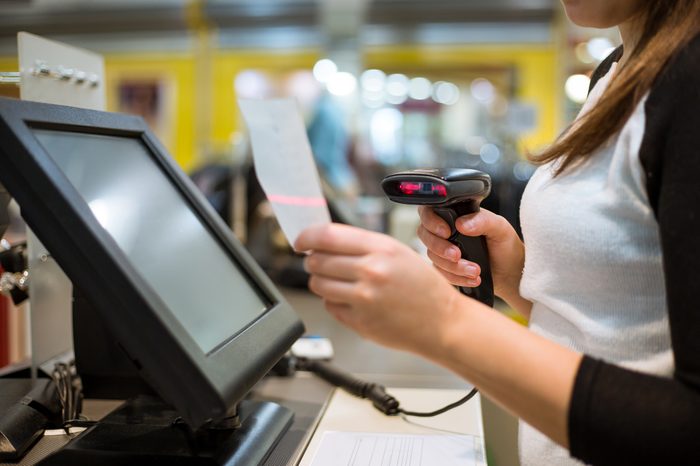 Young woman hands scaning / entering discount / sale on a receipt, touchscreen cash register, market / shop