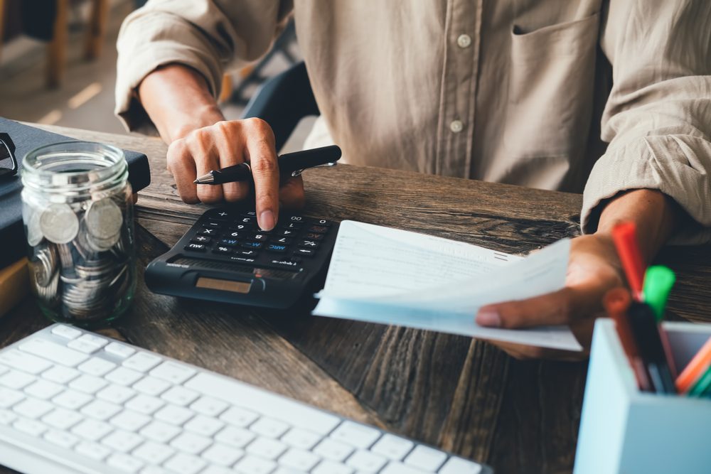 asian man working with calculator to calculate numbers. expenses calculator, payments costs with paper notes, payments table. Financial and Installment payment concept. Saving concept