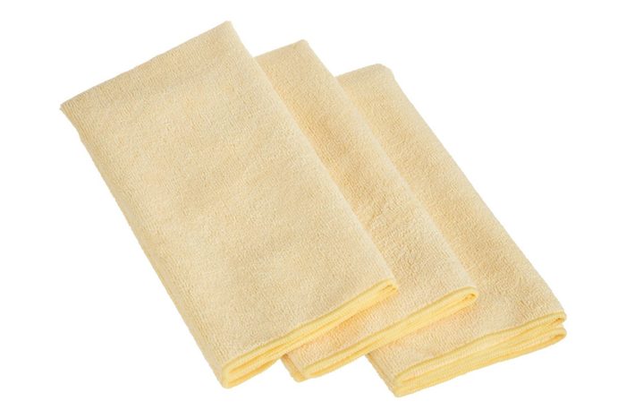 Three folded beige towels lying on a white surface.