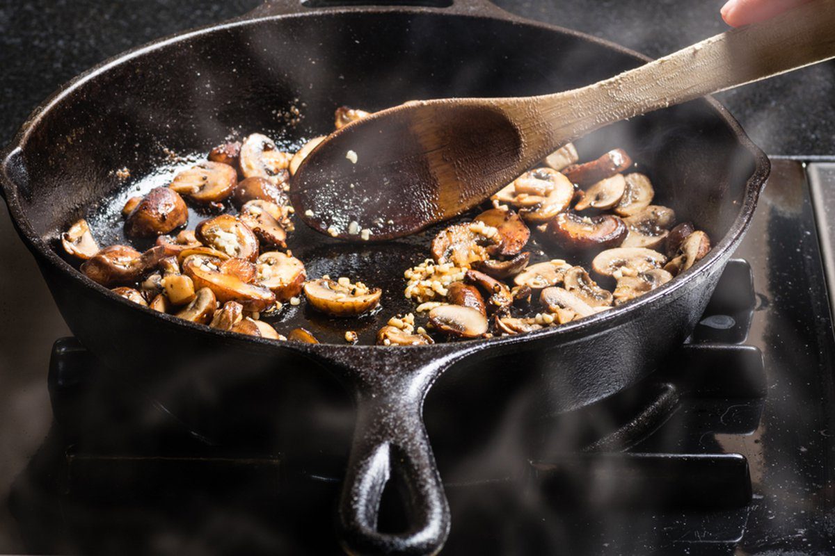 Sautéing sliced mushrooms in a cast iron skillet