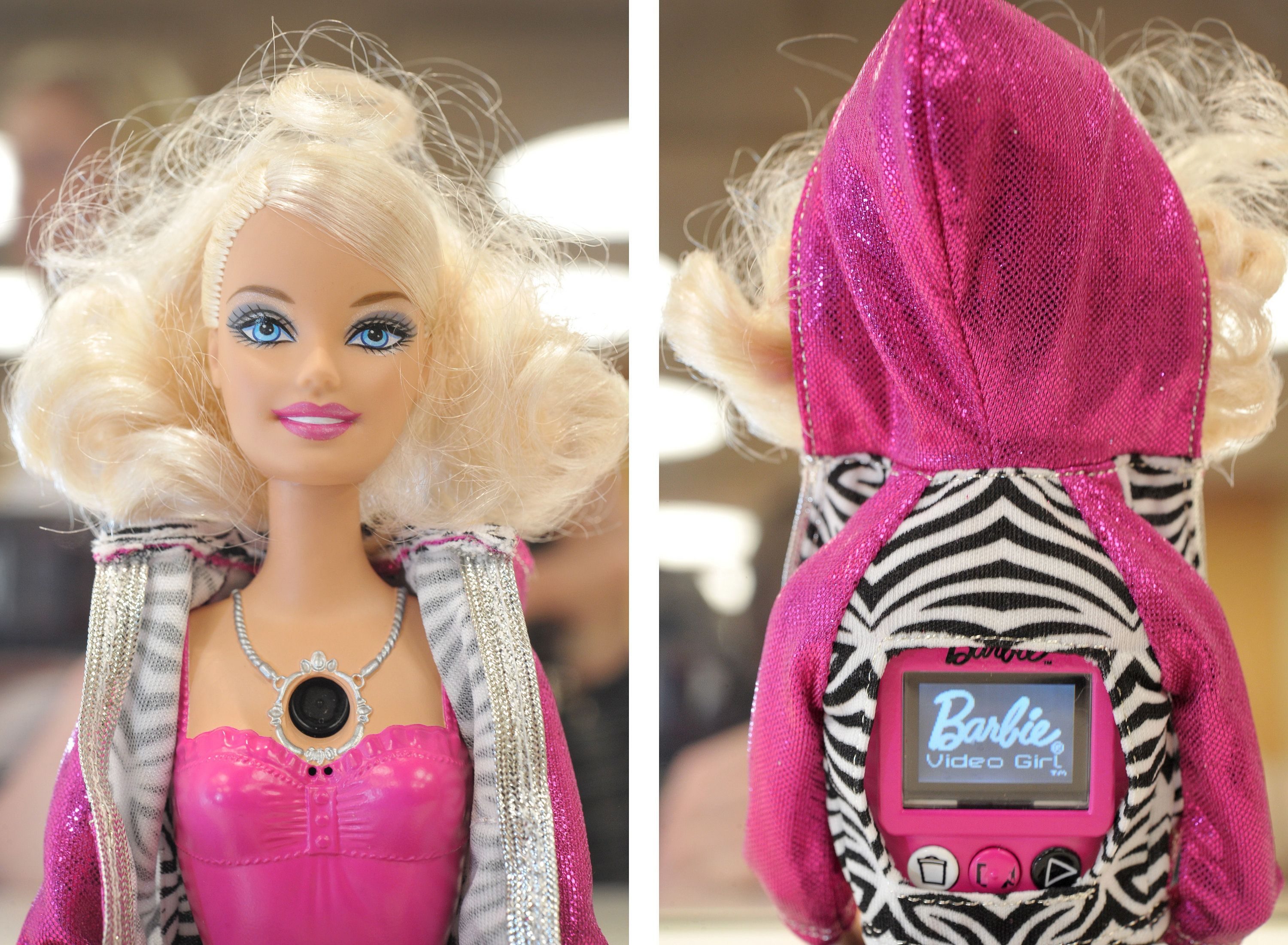 Doll wears pink and silver outfit, displaying a camera on chest. Back reveals "Barbie Video Girl" screen surrounded by zebra-print hood.