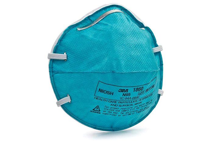 Teal N95 mask lies resting, displaying text with specifications and brand, surrounded by a plain white background.
