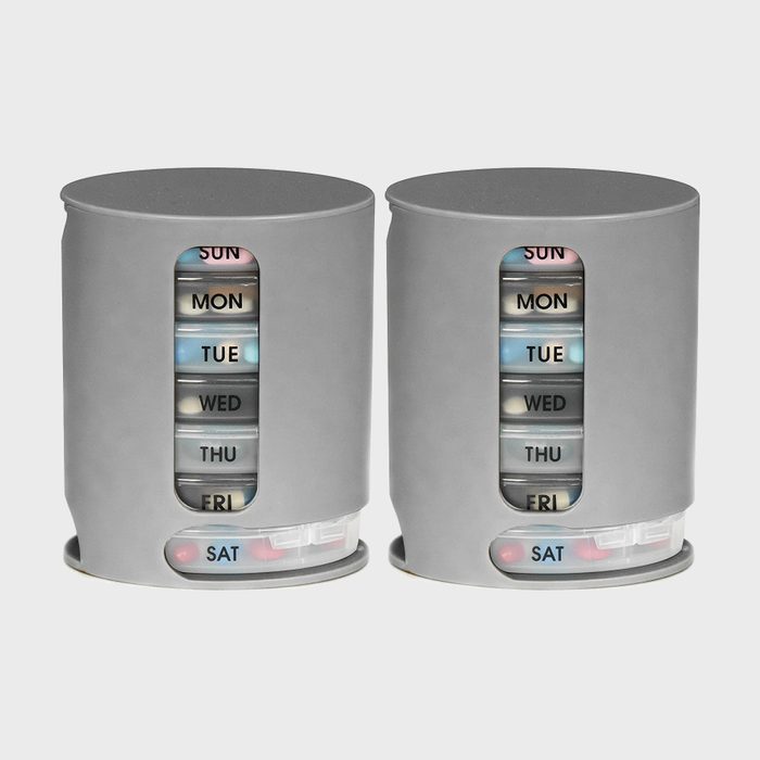 Two cylindrical pill organizers holding day-labeled compartments, standing on a plain background.