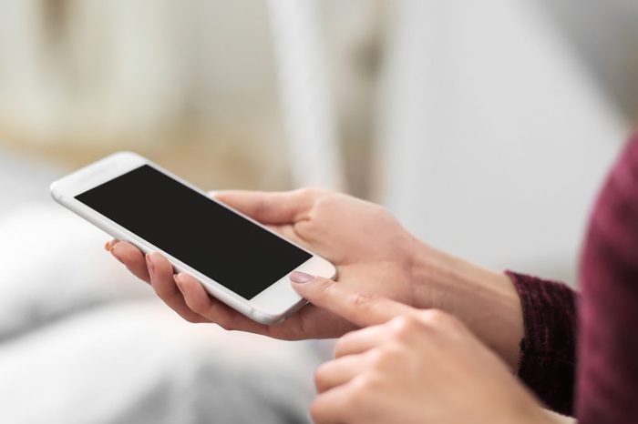 Young woman with mobile phone at home, closeup