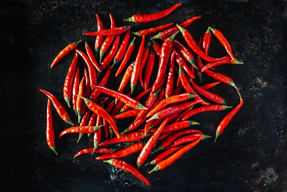 Red chili peppers on old black metal background.