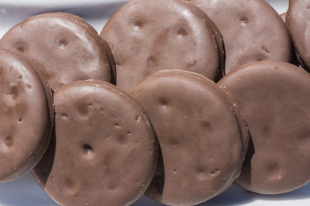 Chocolate-covered cookies arranged closely together on a white surface.