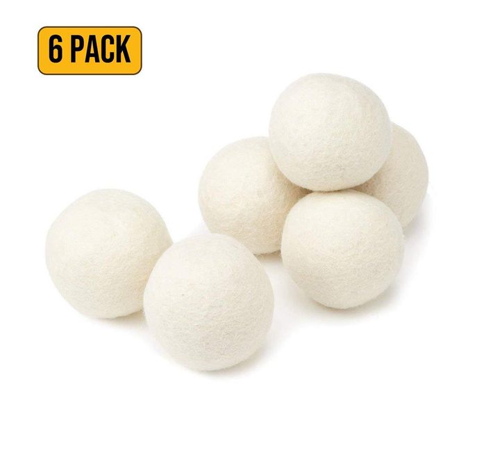 Six white wool balls arranged on a white surface; 