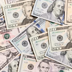 U.S. dollar bills scattered, featuring portraits of historical figures; denominations include five, ten, twenty, fifty, and one hundred, creating a colorful currency collage.
