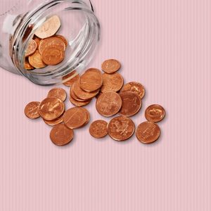 Coins spill from a glass jar, scattering across a pink-striped surface.