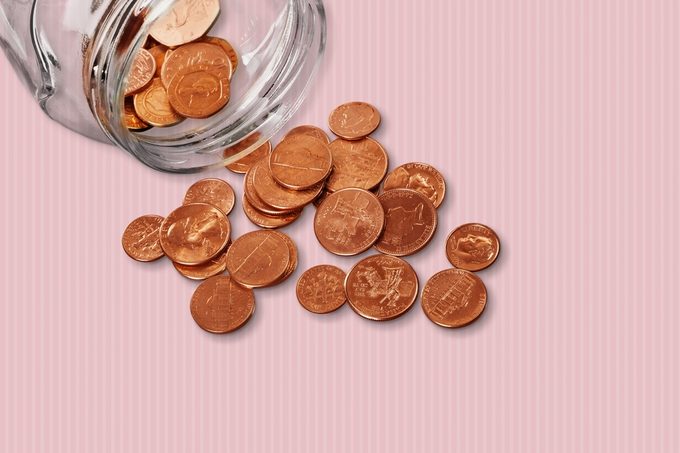 Jar of pennies spilling out on refective white