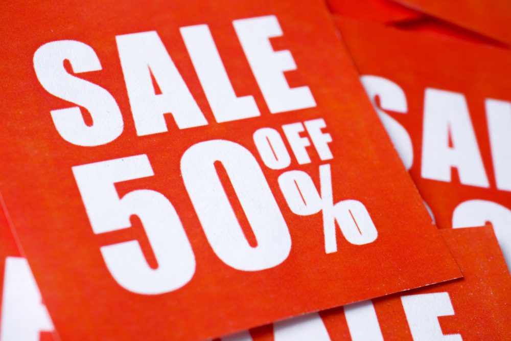 Sign displays "SALE 50% OFF" in bold white letters on a bright red background, overlapping with similar signs.