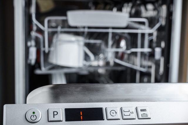 Dishwasher displays "1" on control panel; open rack appears inside kitchen setting.