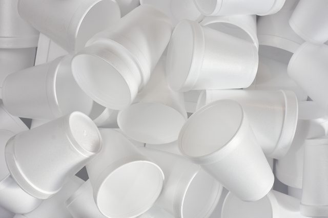 White styrofoam cups are stacked and scattered, creating a jumble on a plain background.