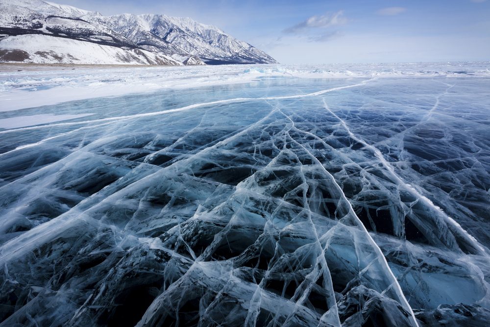View of beautiful drawings on ice from cracks and bubbles of deep gas on surface of Baikal lake in winter, Russia