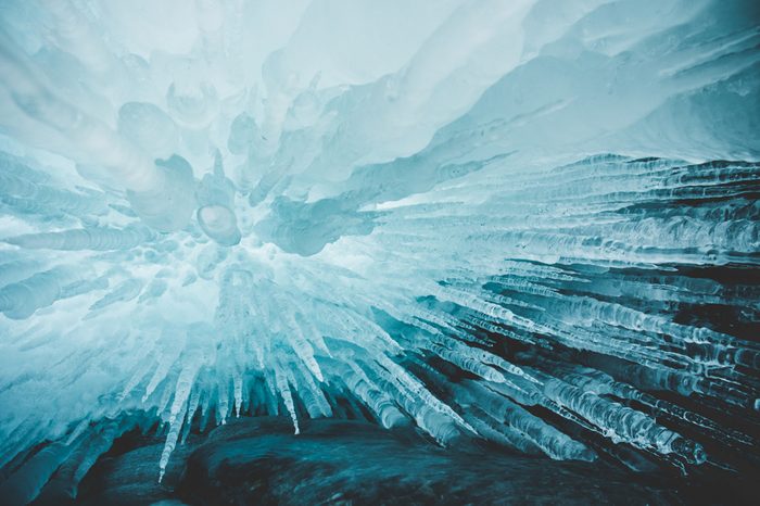 Crystal clear sharp icicles hanging down in frozen cave, lake Baikal, Olkhon island, Siberia, Russia. Beautiful winter wallpaper.
