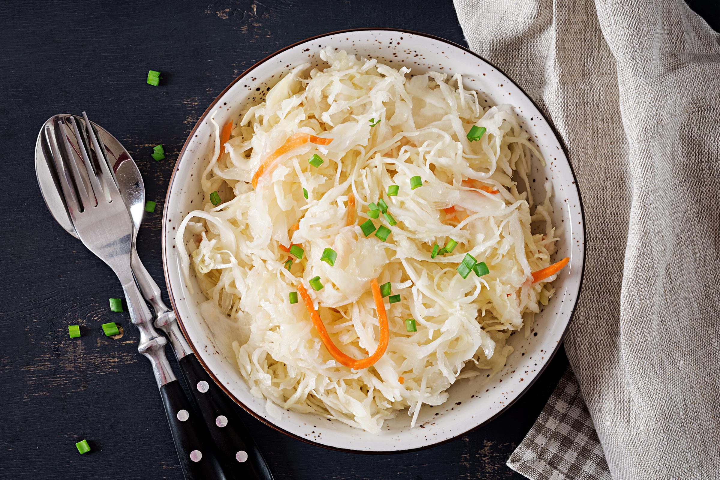 Fermented cabbage. Vegan food. Sauerkraut with carrot and spices in bowl on the dark background. Trend food. Top view . Flat lay, copy space