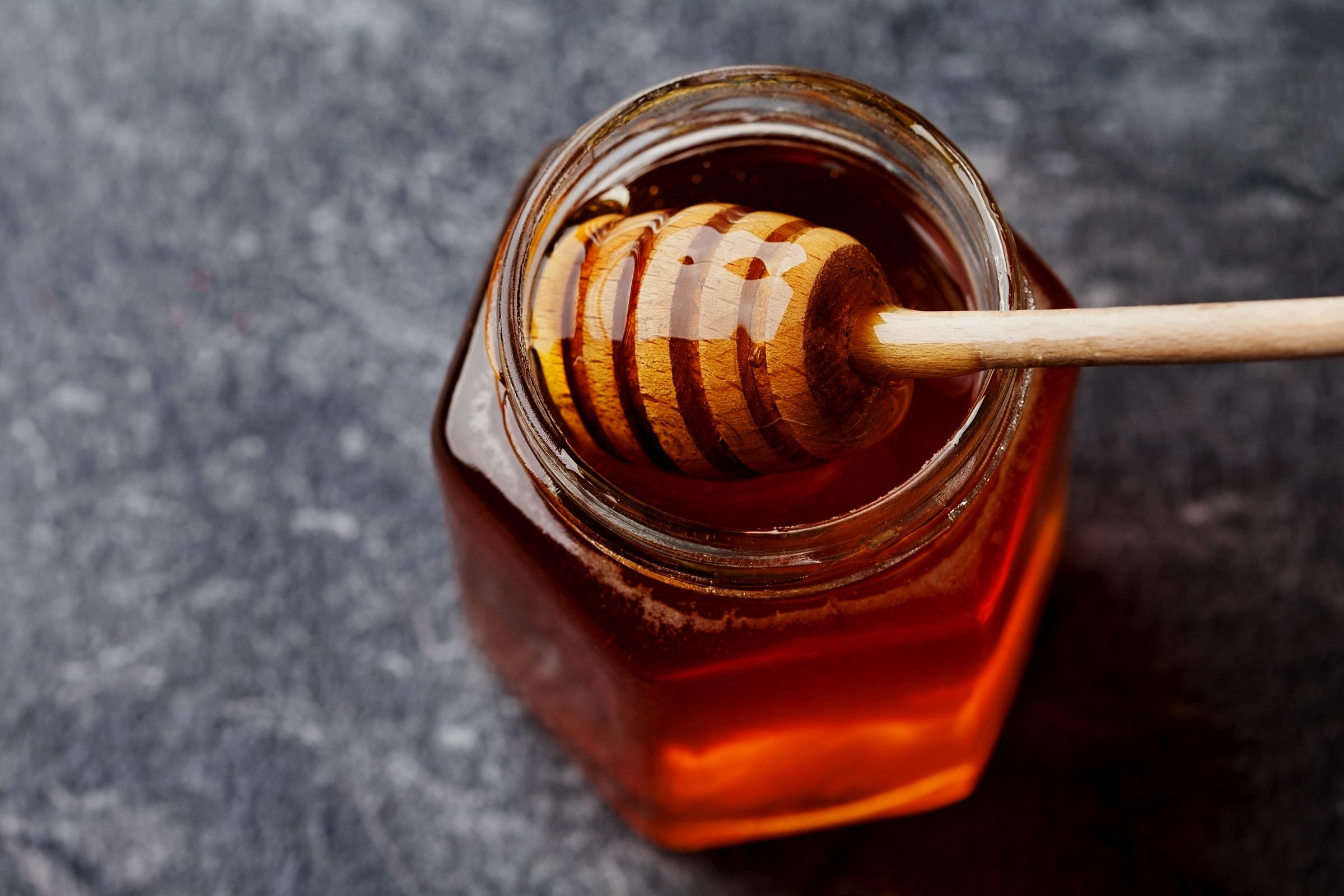 Honey in a pot or jar on kitchen table, top view