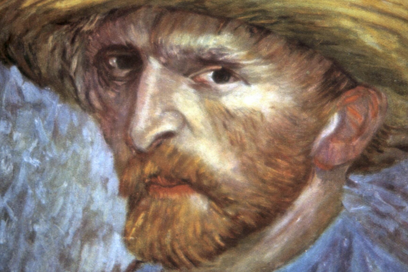 A man with a beard wears a yellow hat, gazing intensely. The background is textured with muted colors, enhancing the portraitâ€™s focus.