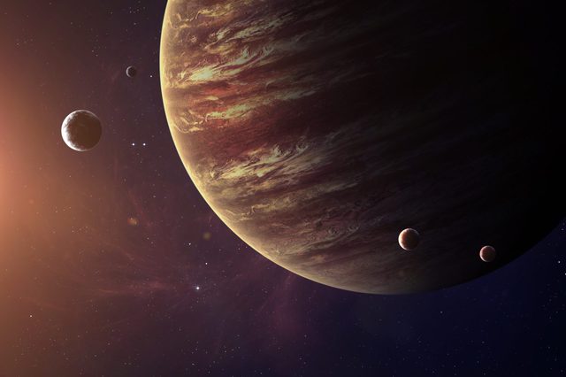 A large gas giant planet dominates the scene, surrounded by smaller moons against a backdrop of stars in deep space.