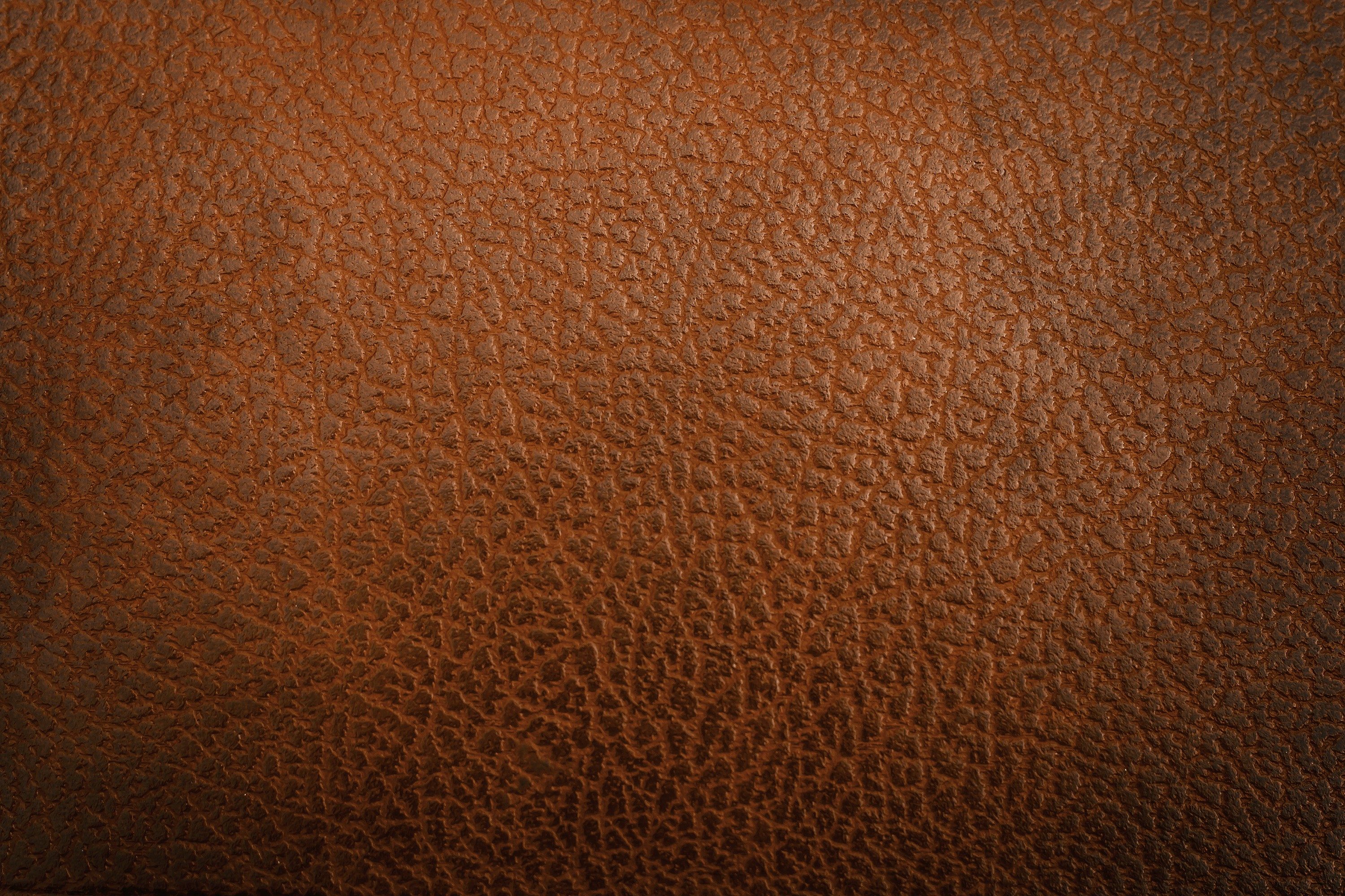 Brown leather displays a textured surface, resembling intricate cracks, in a close-up view.
