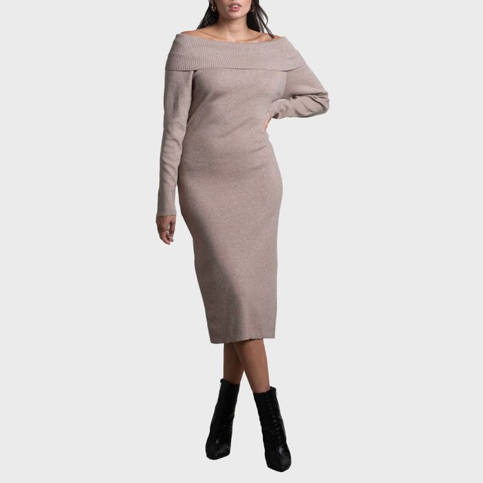 A woman models a long, off-the-shoulder beige dress, standing against a plain background, with black ankle boots.
