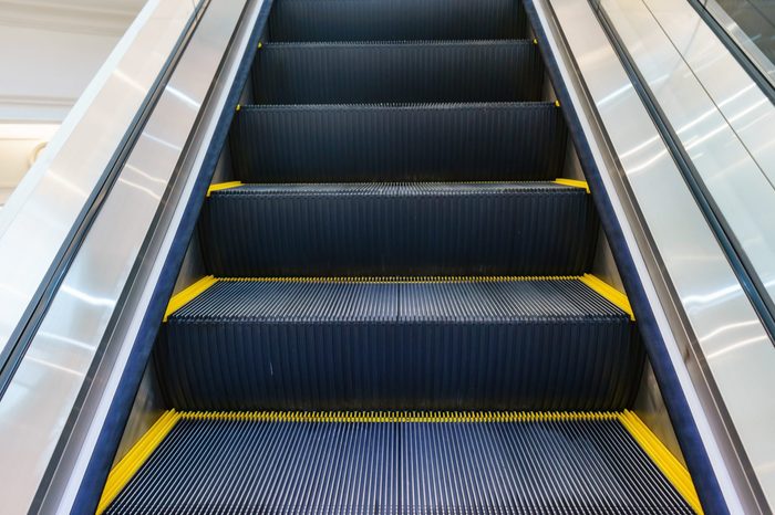 Escalator in Community Mall, Shopping Center. Moving up staircase. electric escalator. Close up to escalators. Close up floor platform. yellow bands. metal line steel. yellow gray steel line.
