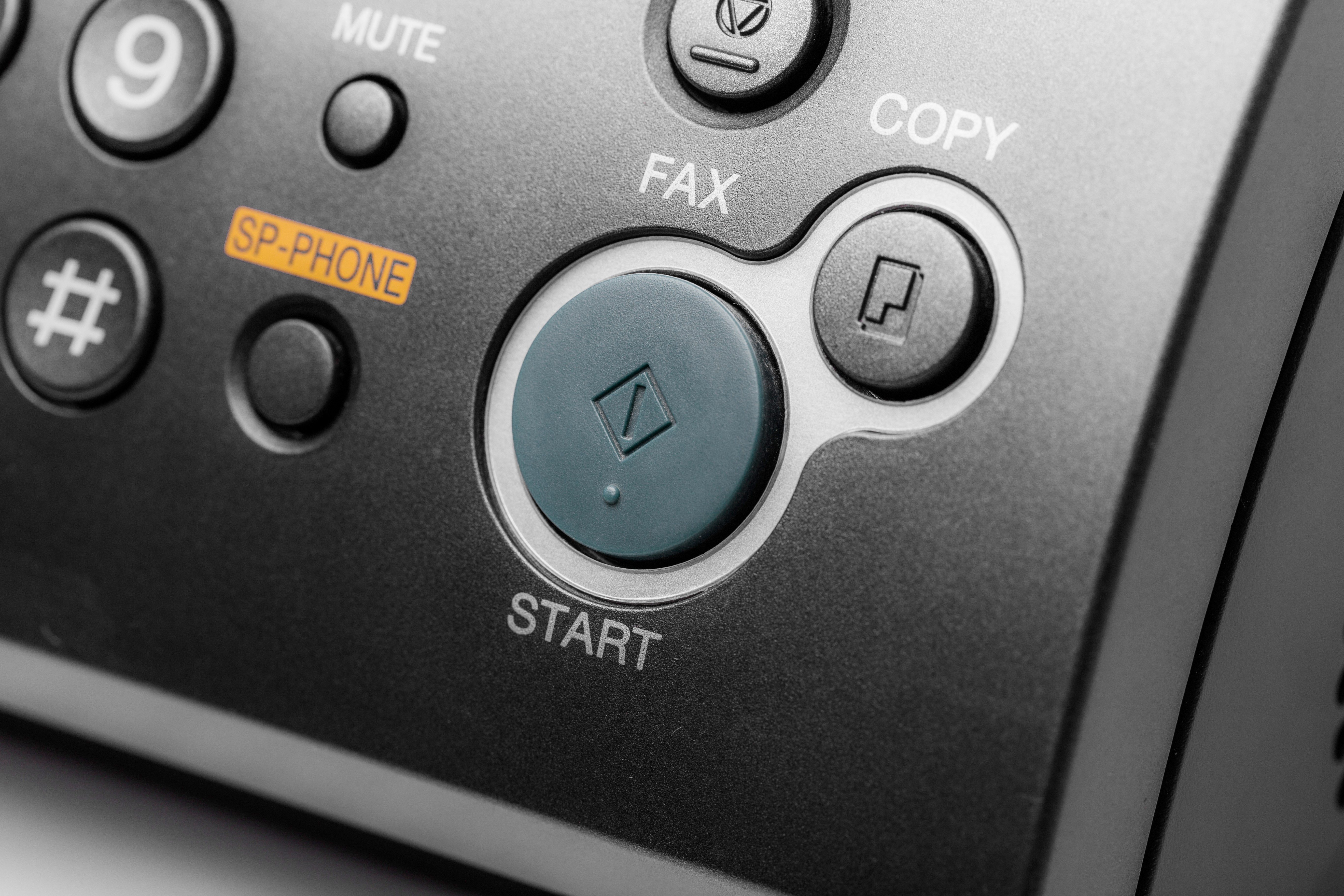 Device's keypad features buttons labeled "FAX," "COPY," "START," "#," "MUTE," "SP-PHONE" in a close-up view, emphasizing communication functions.