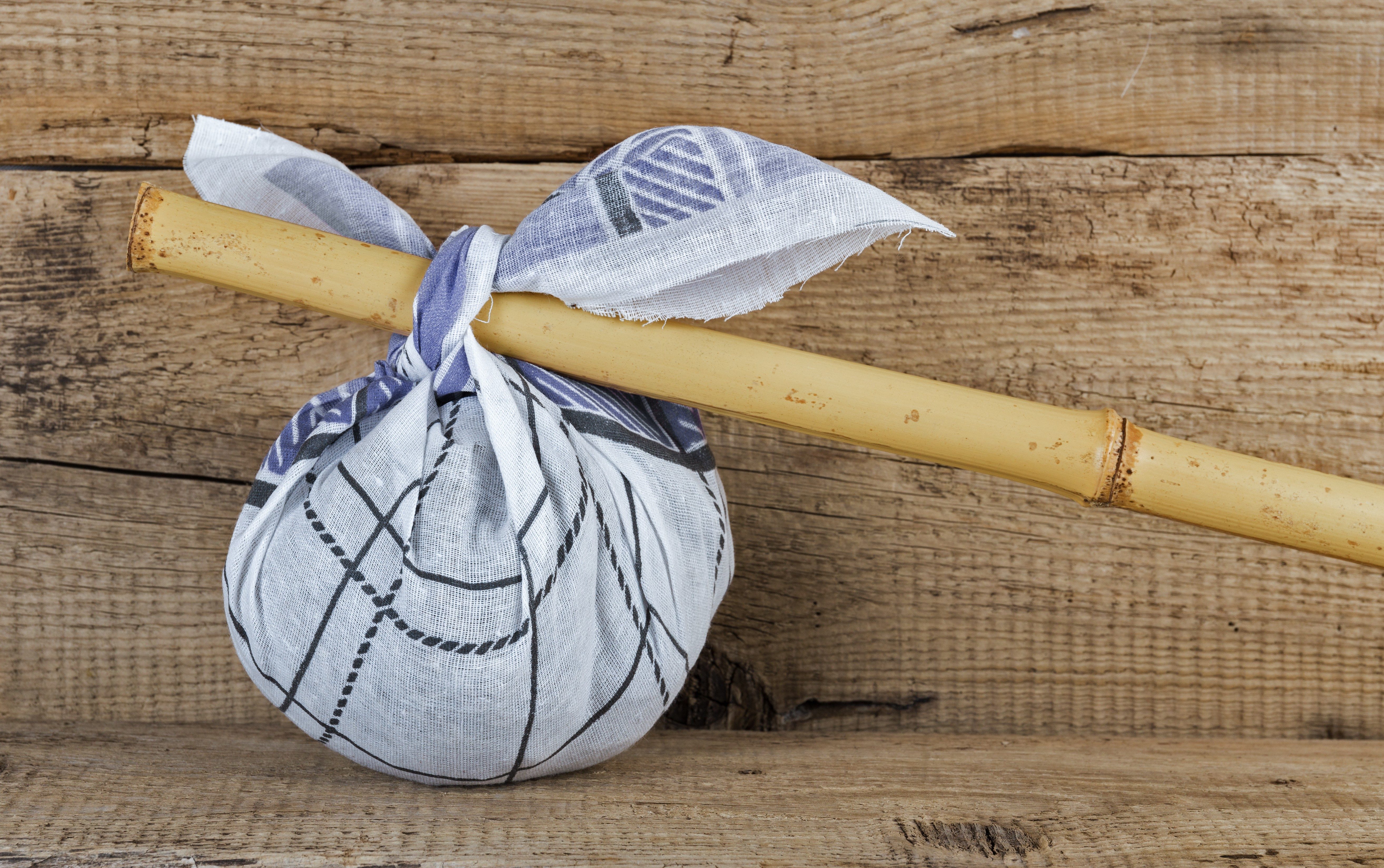 Cloth bundle tied to a wooden stick rests on rustic wooden planks.