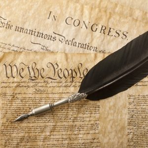 Quill pen rests on aged documents, including 