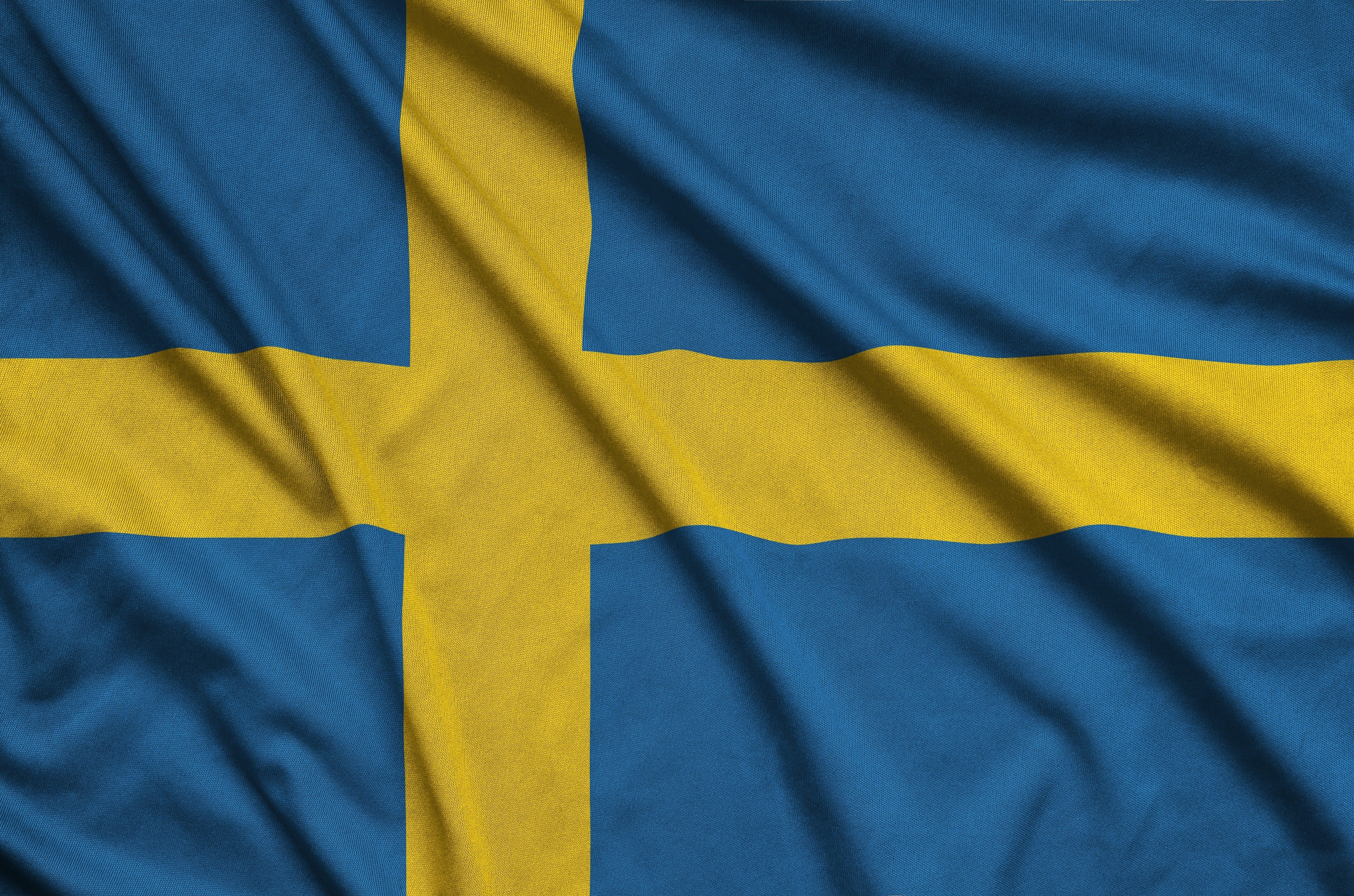 Blue flag displays a yellow Scandinavian cross, slightly crumpled, filling the entire image.