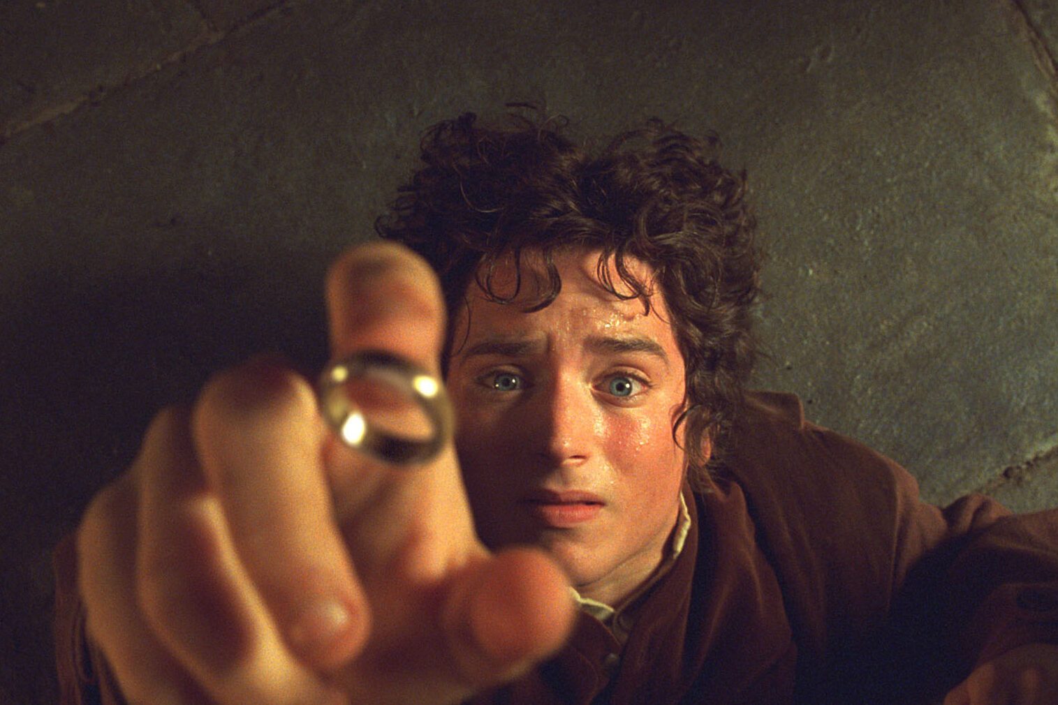 A person reaches for a ring, intensely focused, against a textured stone floor background.