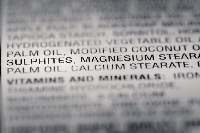 Text listing food ingredients like sulphites and magnesium stearate, highlighted and in focus, surrounded by additional blurred text in a list format.