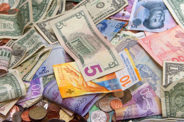 Close up on pile of many bank notes from various countries from around the world. U.S., German, Swiss, Canadian, Brazilian, Vietnamese, Mexican. Many countries represented in currency. Bills and coins