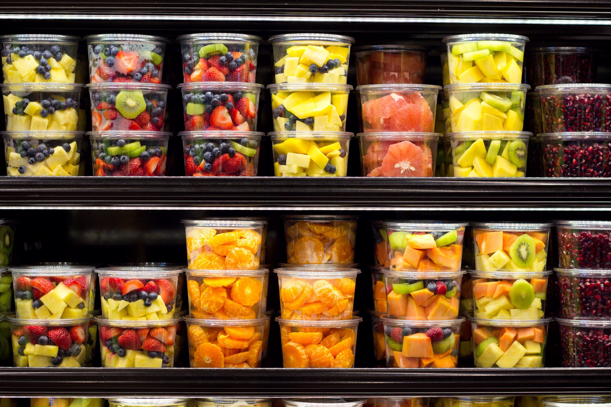 Assortment of cut fruit in containers on display for sale